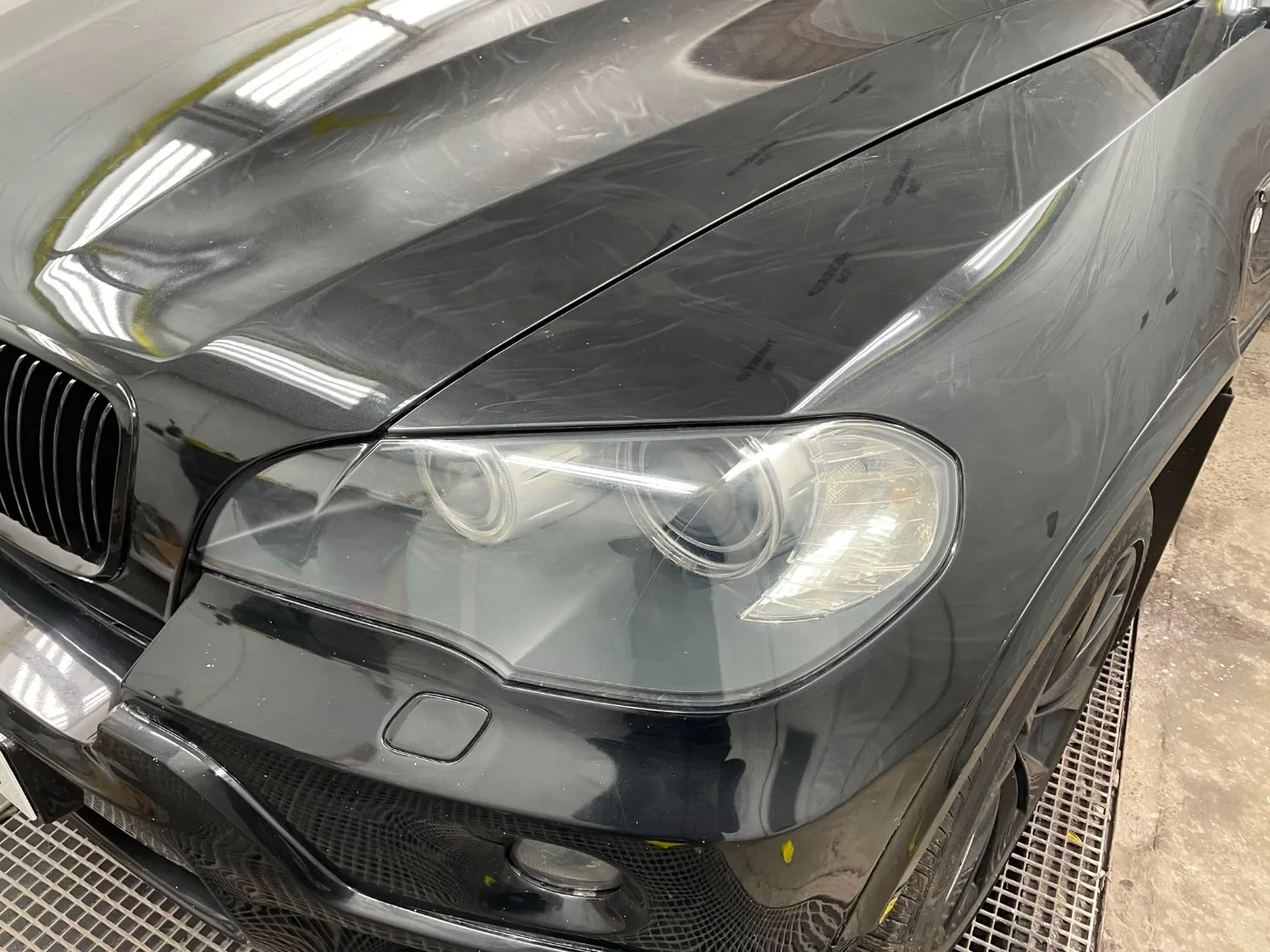 Front wing and bonnet of a black BMW X5 covered in swirl marks and dulled, oxidised paint
